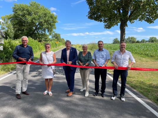 Bernhard Knoop (Leiter LBM Worms), Ortsbürgermeisterin Ute Klenk-Kaufmann, Landrat Heiko Sippel, Isabel Neubauer (Kreistagsfraktion Bündnis 90/Die Grünen), VG-Bürgermeister Steffen Unger und Thomas Finger (Kreisbauamt) (v.l.) beim Durchschneiden des Bandes anlässlich der offiziellen Freigabe des sanierten Straßenabschnittes. Foto: Kreisverwaltung Alzey-Worms /Simone Stier
